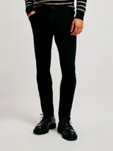 Pantalón de jean negro, corte ajustado (skinny), con tiro medio y cierre de botón y cremallera.