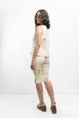 Pantalón capri color crema con estampado de caras y flores, tiro medio y corte ajustado.