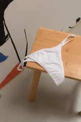 Pantie mínima en color blanco, con elásticos regulables en los costados y corte clásico, confeccionada en microfibra biodegradable.