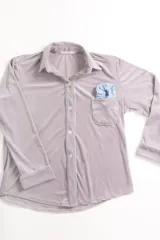 Pijama celeste de terciopelo, compuesto por una camisa de manga larga con botones y vivo blanco, bolsillo en el pecho y un pantalón recto con elástico en la cintura.