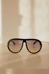 Lentes de sol estilo aviador con marco negro de policarbonato y lentes degradados de violeta a amarillo.