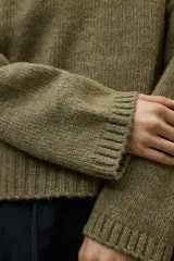 Sweater de punto grueso, color verde oliva, con cuello redondo y manga larga.
