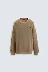Sweater color marrón claro de punto con cuello redondo y manga larga. Presenta roturas en toda la prenda y terminaciones irregulares.