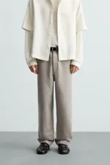 Pantalón de vestir color blanco hueso, de corte recto y tiro medio, con cintura elástica y cierre frontal de botón y cremallera. Presenta bolsillos frontales y bolsillos traseros de vivo.