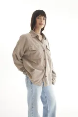 Camisa oversize color beige de pana con cuello clásico, cierre frontal con botones, mangas largas con puños abotonados y dos bolsillos con solapa en el pecho.
