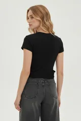 Remera blanca de manga larga, corte ajustado al cuerpo, con cuello redondo y volados en el ruedo. Presenta un estampado frontal en negro con texto y una llave de hotel antigua.