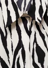 Camisa de manga larga con estampado de cebra en blanco y negro, cuello camisero y cierre frontal con botones.