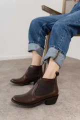 Botín Chelsea de cuero marrón con elástico lateral y tacón bajo.