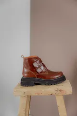 Botas cortas de cuero color hueso, con puntera redondeada, ajuste con doble tira con velcro color verde oliva y suela track color negro.