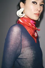 Pañuelo cuadrado de modal y seda con estampado de amapolas en tonos rojos y fucsias, y borde blanco.