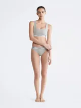 Corpiño deportivo Calvin Klein color gris, sin relleno, con escote en U, espalda cruzada y banda elástica con logo.
