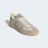 Championes Adidas Handball Spezial color beige con detalles en gris y suela de goma color caramelo. Presentan las tres tiras características de la marca en los laterales y la inscripción "Spezial" en letras doradas.