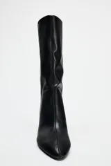 Bota de cuero sintético color negro, con caña media de efecto arrugado, punta fina y tacón fino.