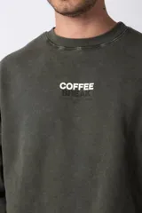 Buzo marrón de algodón rústico con lavado gastado y cuello redondo. Estampa frontal con la frase "Coffee Break". Corte oversize.