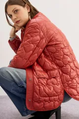 Campera color ladrillo con matelassé de corazones, corte amplio, mangas largas y bolsillos con solapa y botones snap en el frente.