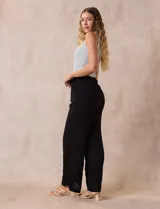 Pantalón negro de rayón con bordados florales, pretina ancha elastizada en punto smock y corte palazzo. Marca Liv Los Angeles.