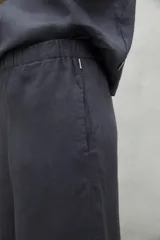 Pantalón de lino color beige, de pierna ancha, cintura elástica y bolsillos laterales.