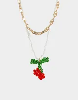 Collar corto multicadena, con una cadena dorada de eslabones grandes y otra de mostacillas blancas, con dije de cerezas rojas y hojas verdes hechas de mostacillas.