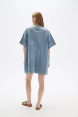 Vestido corto de jean celeste, de corte holgado, manga corta y cuello redondo.