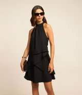 Vestido corto negro con escote halter y volados superpuestos en la falda.