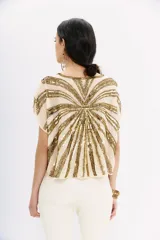 Blusa color crema con escote en V y mangas cortas tipo kimono. Presenta un diseño de rayas horizontales con lentejuelas doradas.