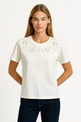 Remera color crudo de manga corta con cuello redondo y bordado calado en el frente.