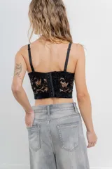 Corset crop negro de encaje con lentejuelas bordadas, estructura interna, copas armadas, breteles regulables y cierre trasero.