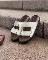 Sandalias bajas de cuero color marrón con doble tira ancha en el empeine.