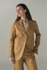 Blazer lila de lino con ruedo curvo, solapas con muesca, cierre frontal con un botón, bolsillos ojal con solapa y tajo en la espalda.