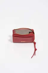 Monedero pequeño de estructura rígida, color negro, con cierre de cremallera y tirador de tejido amarillo mostaza. Presenta un bolsillo exterior frontal y el logo de la marca grabado en dorado.