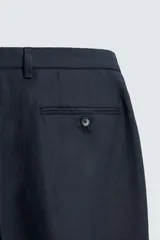 Pantalón de vestir color beige claro, confeccionado en lino, de corte recto, con bolsillos laterales y traseros.