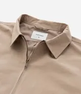 Campera masculina color marrón confeccionada en sarga, con cuello inglés, cierre de cremallera frontal, manga larga y bolsillos con detalles.