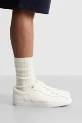 Zapatillas de cuero blanco con cordones y suela plana.