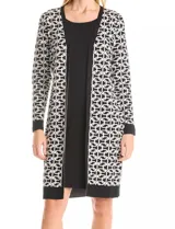 Vestido de tejido de punto marca Nina Leonard, con diseño Twofold que simula un conjunto de vestido negro liso y cárdigan largo con estampado geométrico blanco y negro. Presenta escote redondo y manga larga de corte recto.