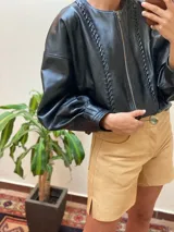 Campera marrón de cuero con cierre frontal, corte oversize, mangas abullonadas y puños ajustados.