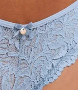 Bombacha de bikini color celeste, de encaje rústico floral, con lazo y dije colgante.