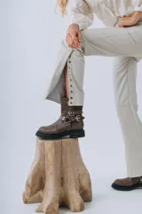 Botas cortas de cuero color marrón con suela track, caña baja y múltiples correas con hebillas metálicas.