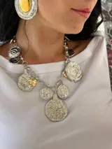 Collar plateado con cadena de eslabones y dijes colgantes con detalles dorados.