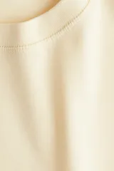 Remera color crema de algodón, de corte amplio, con cuello redondo y mangas cortas.