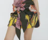 Minifalda estampada con flores en tonos rosa, amarillo, verde y negro. Presenta un lazo en la cintura para ajustar y cerrar la prenda.