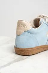 Zapatillas bajas de gamuza celeste con cordones blancos y suela de goma marrón.