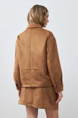 Chaqueta color tostado simil gamuza con cuello clásico, cierre con botones a presión, bolsillos de parche en el pecho y corte recto.