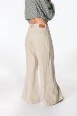 Pantalón jean color beige, de corte recto y tiro alto, con bolsillos delanteros y traseros, y detalle desflecado en los laterales.