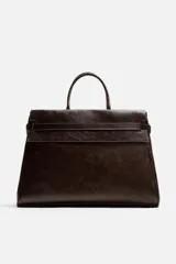 Bolso de mano extragrande color marrón oscuro, fabricado en piel de alta calidad. Tiene un compartimento principal con cierre magnético, un bolsillo interior con cremallera y un bolsillo secundario con solapa y cinta. Las asas son de piel.
