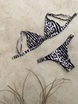 Conjunto de bikini blanco con textura, compuesto por un corpiño de triángulo fijo con breteles regulables y almohadillas desmontables, y una bombacha vedetina con frunce elástico en los costados.