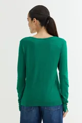 Cárdigan negro de tejido de punto fino con escote en V, cierre frontal con botones dorados y mangas largas con puños ajustados.