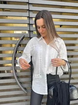 Camisa blanca de mangas largas con detalles de encaje en el frente, cuello y puños.