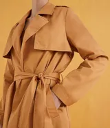 Campera trench coat larga color camel, con cuello con solapa, manga larga, abertura frontal con doble botonadura, dos bolsillos laterales, trabillas en la cintura y cinturón para amarrar.