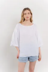 Blusa color beige confeccionada en lino, de corte holgado, mangas 3/4 y cuello redondo.