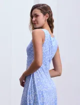 Vestido midi de lunares blancos sobre fondo celeste, marca Sandra Darren. Tiene cuello alto cruzado con abertura ojal y aplique metálico. Corte en la cintura y falda acampanada. Sin mangas.